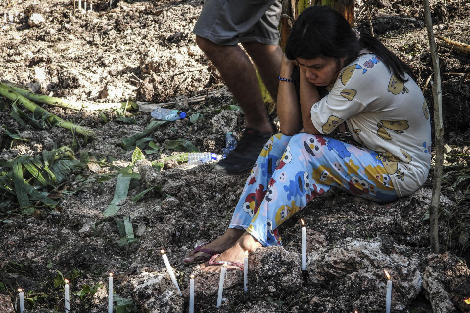 A woman grieves in front of the burial site of her relatives that were retrieved after Tropical Storm Nalgae hit Barangay Kusiong, Datu Odin Sinsuat, Maguindanao province, southern Philippines on Monday Oct. 31, 2022. Philippine officials say more than 100 people have died in one of the most destructive storms to lash the Philippines this year. (AP Photo)