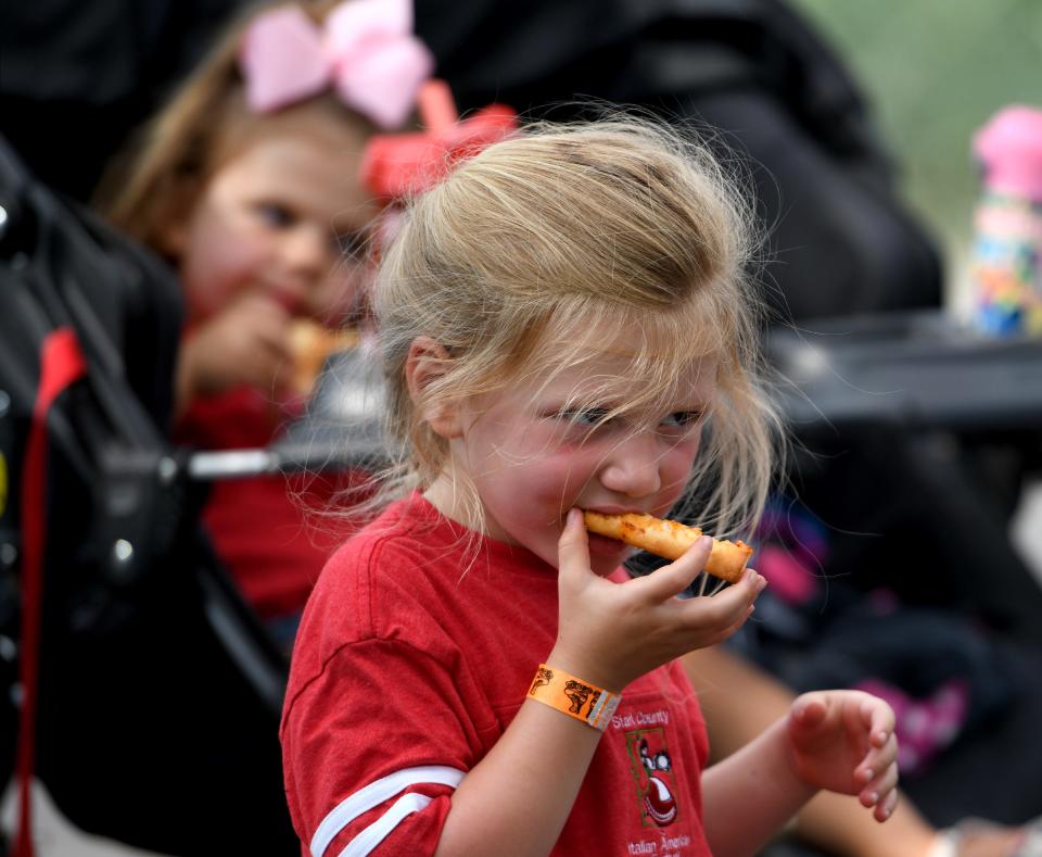 Sophia Durnell, 4, of Green finishes a slice of pizza at the 35th Stark County Italian American Festival at Centennial Plaza in downtown Canton.  Friday, July 07, 2023.