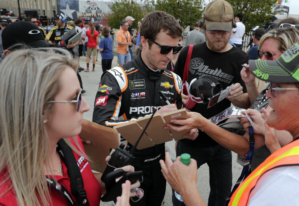 Kasey Kahne signs autographs for fans as he prepares to participate in qualifying for a NASCAR Cup series auto race in Fort Worth, Texas, Friday, April 6, 2018. (AP Photo/Tony Gutierrez)