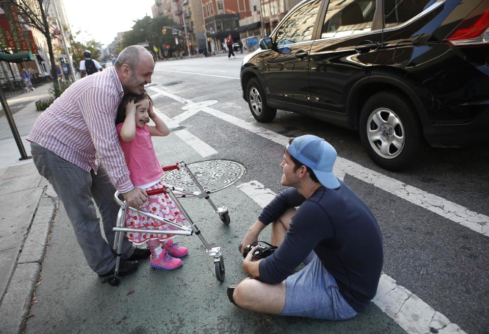 This Oct. 2, 2013 photo shows photographer Brandon Stanton, creator of the Humans of New York blog, right, after snapping a portrait of Mecit Kabatas and his five year-old daughter Bayza in New York. Stanton’s magical blend of portraits and poignant, pithy storytelling has earned HONY more than 2 million followers online. Now he’s putting his work in a book, “Humans of New York,” due out Oct. 15 from St. Martin’s Press. (AP Photo/Kathy Willens)