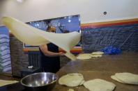 A worker waves the dough as he prepares pastry sheets of sambusa snacks during the holy month of Ramadan in Sanaa