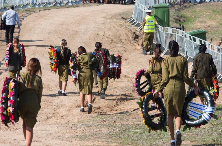 Israeli soldiers carry wreaths of flowers for the burial ceremony of former Israeli prime minister Ariel Sharon as his body arrives at the grave site on January 13, 2014 at the family ranch Havat Shikmin