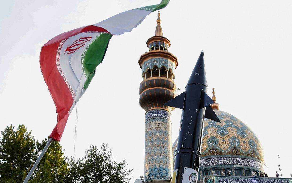 Iranians lift up a flag and the mock up of a missile during a celebration following Iran's missiles and drones attack on Israel