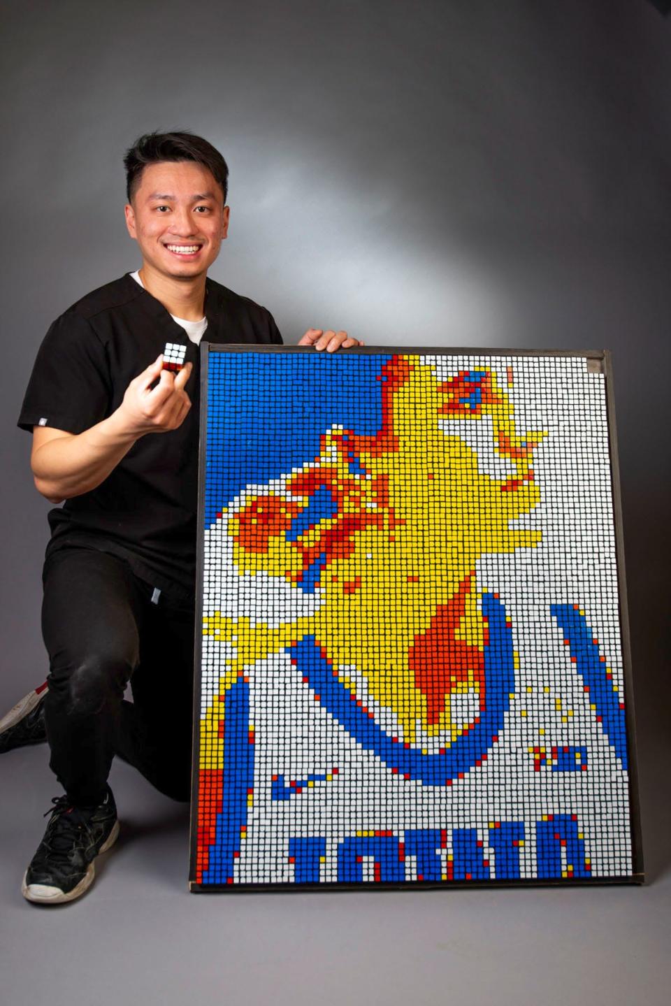 Brain Dang stands next to his portrait of Caitlin Clark, crafted out of 720 Rubik's Cubes, at the University of Iowa College of Dentistry in Iowa City on Wednesday, April 3, 2024.