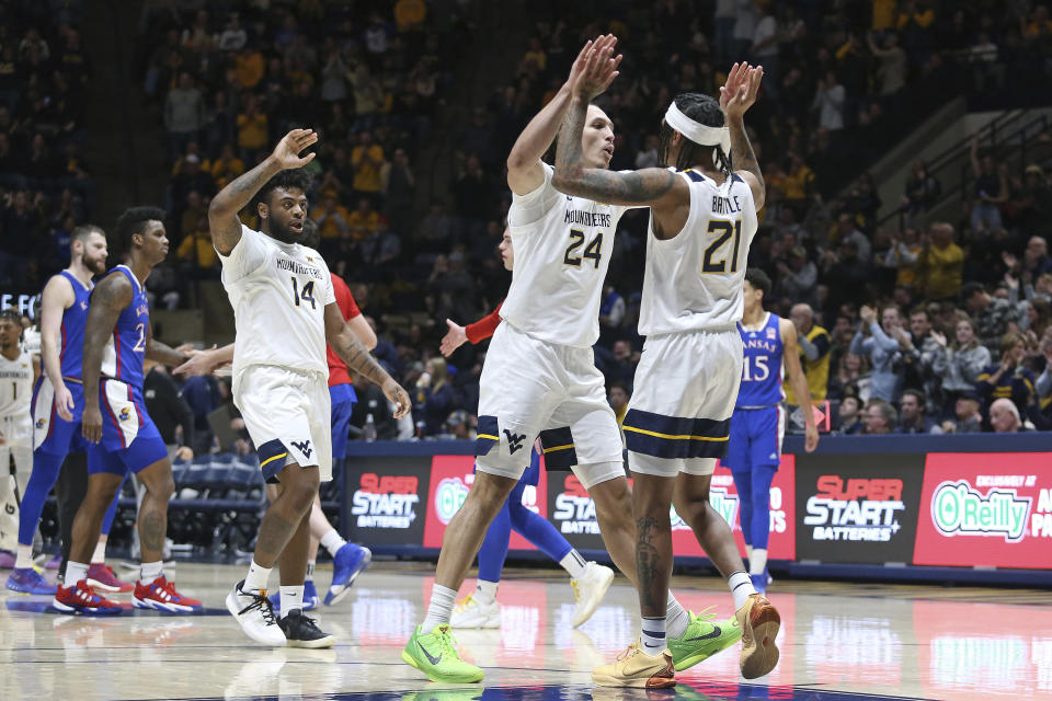 West Virginia guard Seth Wilson (14), forward Patrick Suemnick (24), and guard RaeQuan Battle (21) celebrate during the second half of an NCAA college basketball game against Kansas, Saturday, Jan. 20, 2024, in Morgantown, W.Va. (AP Photo/Kathleen Batten)