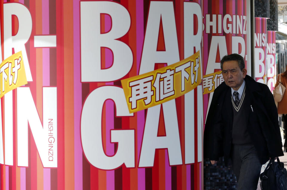 In this Jan. 28, 2014 photo, a man walks by a shopping mall pillars decorated with bargain sale advertisements, offering further price reduction, in Tokyo. Japan's consumer price index rose 0.4 percent in 2013, the first increase in five years, in further evidence the recovery in the world's third-largest economy is gaining momentum. (AP Photo/Shizuo Kambayashi)