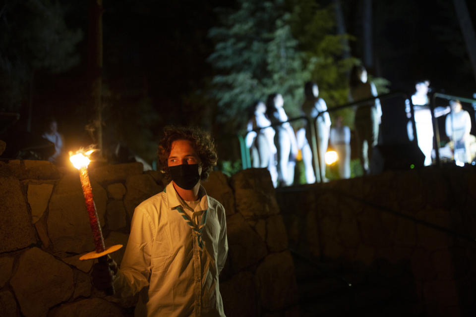 An Israeli scout holds a torch during a Memorial Day ceremony commemorating fallen soldiers, at the military cemetery at Mount Herzl in Jerusalem, Tuesday, April 13, 2021. (AP Photo/Maya Alleruzzo)