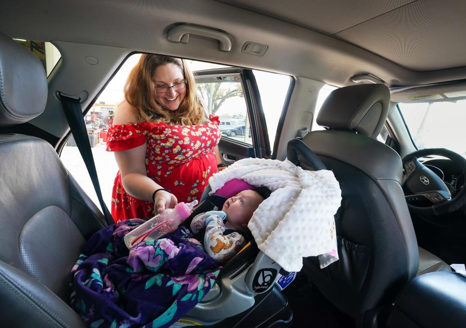 Ashley Lewin of North Port feeds her three-month-old baby, Morrigan, after getting her car's oil changed at Suncoast Community Church. Lewin, who recently lost her job, said she's glad to have one expense that she doesn't have to worry about.