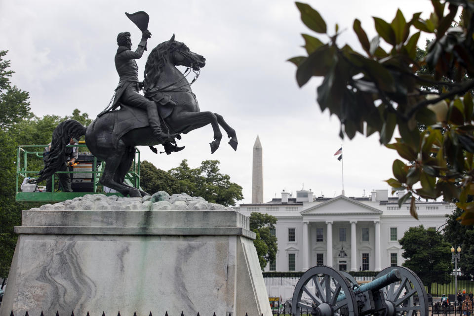 With the White House and the Washington Monument in the background, a National Park Service worker cleans a statue of President Andrew Jackson, Thursday, June 11, 2020, near the White House in Washington, after protests over the death of George Floyd, a black man who was in police custody in Minneapolis. Floyd died after being restrained by Minneapolis police officers. (AP Photo/Jacquelyn Martin)