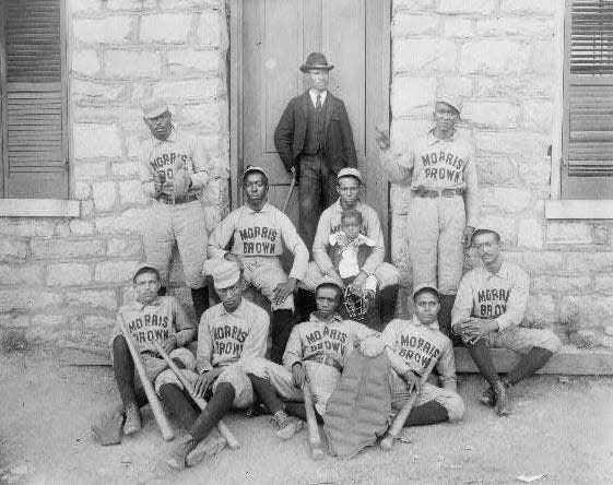 African American baseball players from Morris Brown College, with boy and another man standing at door, Atlanta, Georgia