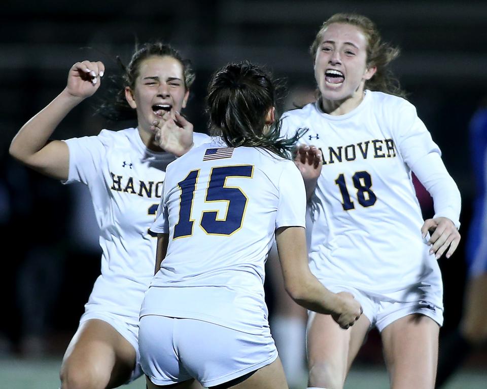 Hanover’s Callie Baldwin and Hanover’s Sophie Schiller rush to hug Hanover’s Sophia Foley after she scored the winning goal in double overtime to give them the 2-1 win over Dover-Sherborn in the Division 3 girls soccer state semifinal game at Manning Field in Lynn on Wednesday, November 15, 2023. Hanover would go on to win 2-1 in double overtime.