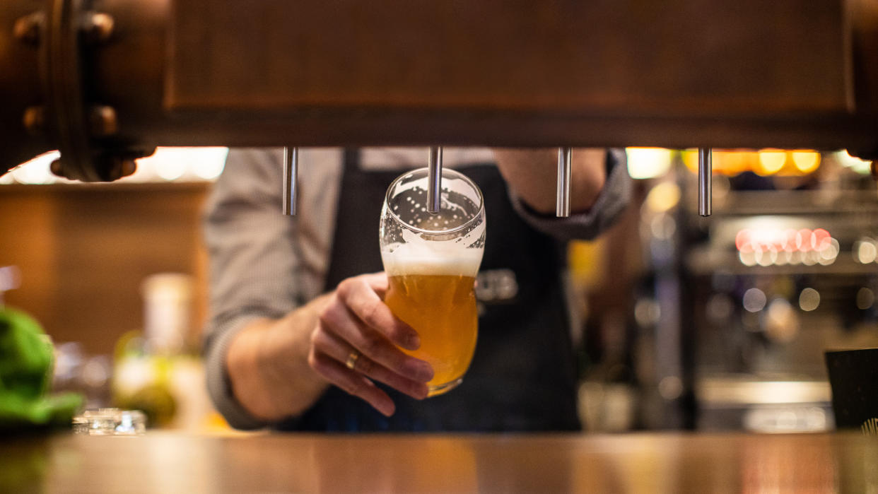 Unrecognizable man pouring a beer on beer tap in drinking glass, in a pub.