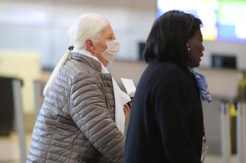 A woman wears a mask as she walks through the international terminal at LAX airport in Los Angeles