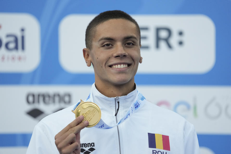 First placed Romania's David Popovici celebrates on the podium of the men's 100m freestyle final at the European swimming championships, in Rome, Saturday, Aug. 13, 2022. (AP Photo/Andrew Medichini)