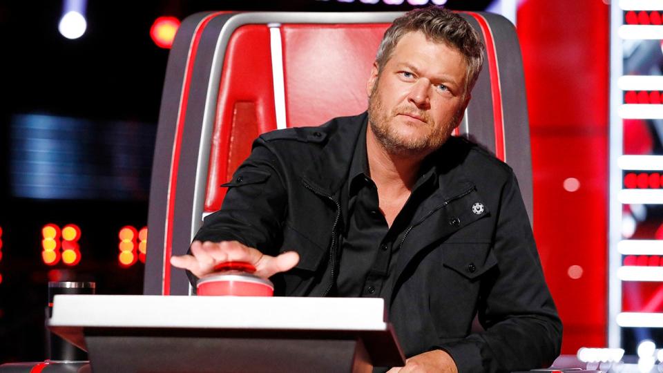 Blake Shelton, wearing a black jacket, presses a button to turn his chair on 