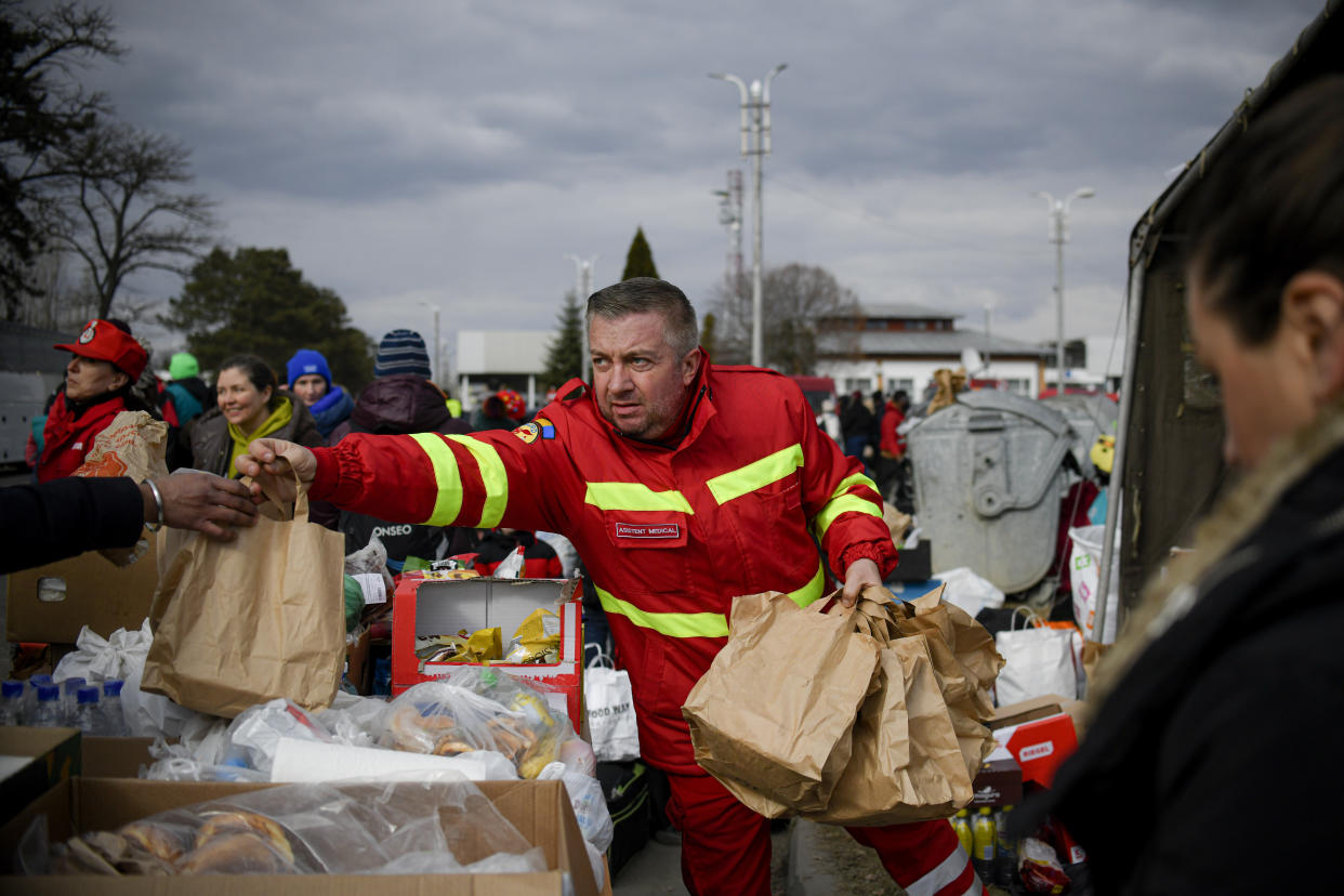 An employee of the Mobile Emergency Service for Resuscitation and Extrication, SMURD, hands out bags of food to refugees that fled the conflict from neighbouring Ukraine at the Romanian-Ukrainian border, in Siret, Romania, Feb. 27, 2022. (AP Photo/Andreea Alexandru, File)