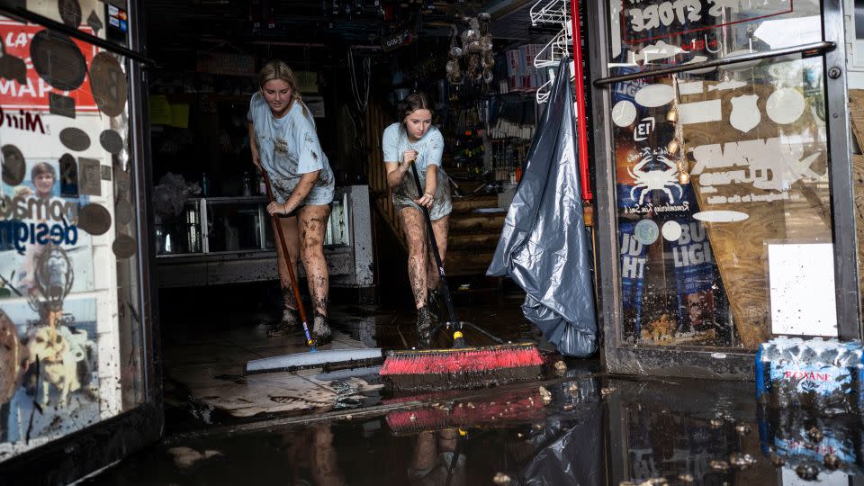 Katie Cole, left, and sister Savannah Cole clean mud out of the Sea Hag Marina gift shop, where they work as cashiers, in Steinhatchee, Florida on Thursday. - Thomas Simonetti for The Washington Post/Getty Images