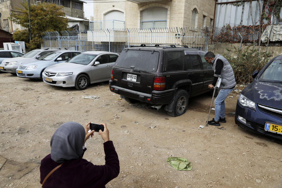 A woman photographs a vandalized vehicle in the Sheikh Jarrah neighborhood of east Jerusalem, Friday, Nov. 19, 2021. Residents from the tense Jerusalem neighborhood say the car tires of 11 Palestinian-owned vehicles were slashed by Israeli settlers. Palestinian families from the neighborhood are currently embroiled in a high-profile eviction case against Israeli settlers. (AP Photo/Mahmoud Illean)