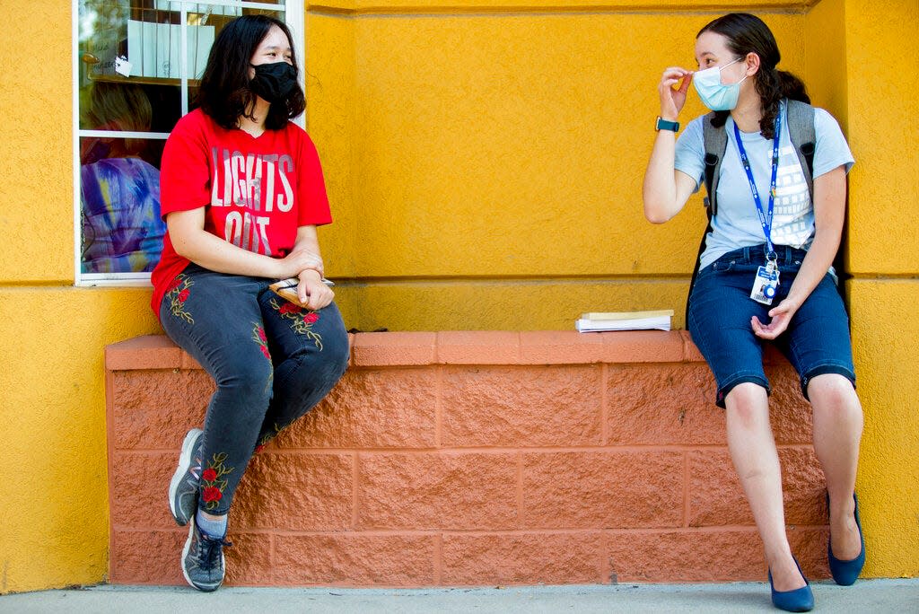 Aurora Golden-Appleton adjusts her face mask as she chats with Rylin Green, both of Provo, as they sit outside Joe Vera's Mexican Restaurant in downtown Provo in August 2020. Some health officials are calling for a return to masks this holiday season, with warnings that a "tripledemic" of COVID-19, RSV and the flu threaten to fill hospitals statewide with patients.