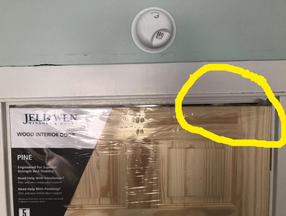 A new wooden door with protective plastic covering doesn't fit