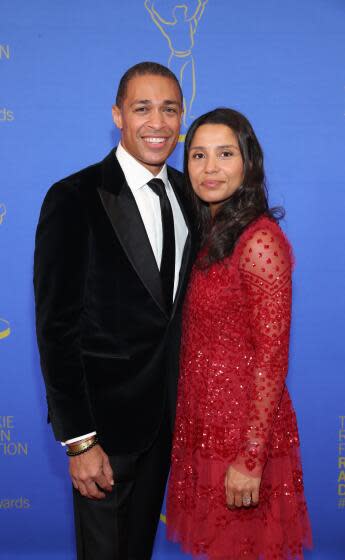 T.J. Holmes and Marilee Holmes smile and pose together, while TJ is wearing a suit and Marilee is in a red dress