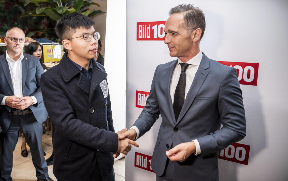 FILE - In this Sept. 9, 2019, file photo, German Foreign Minister Heiko Maas, right, and Hong Kong activist Joshua Wong, left, shake hands during a reception of a German newspaper in Berlin, Germany. Overseas, Joshua Wong has emerged as a prominent face of Hong Kong's months-long protests for full democracy. At home, he is just another protester. (Michael Kappeler/dpa via AP, File)