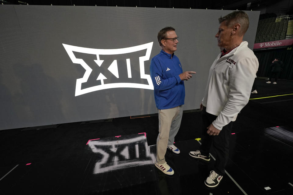 Kansas coach Bill Self, left, talks to Oklahoma coach Porter Moser during the NCAA college Big 12 men's basketball media day Wednesday, Oct. 18, 2023, in Kansas City, Mo. (AP Photo/Charlie Riedel)