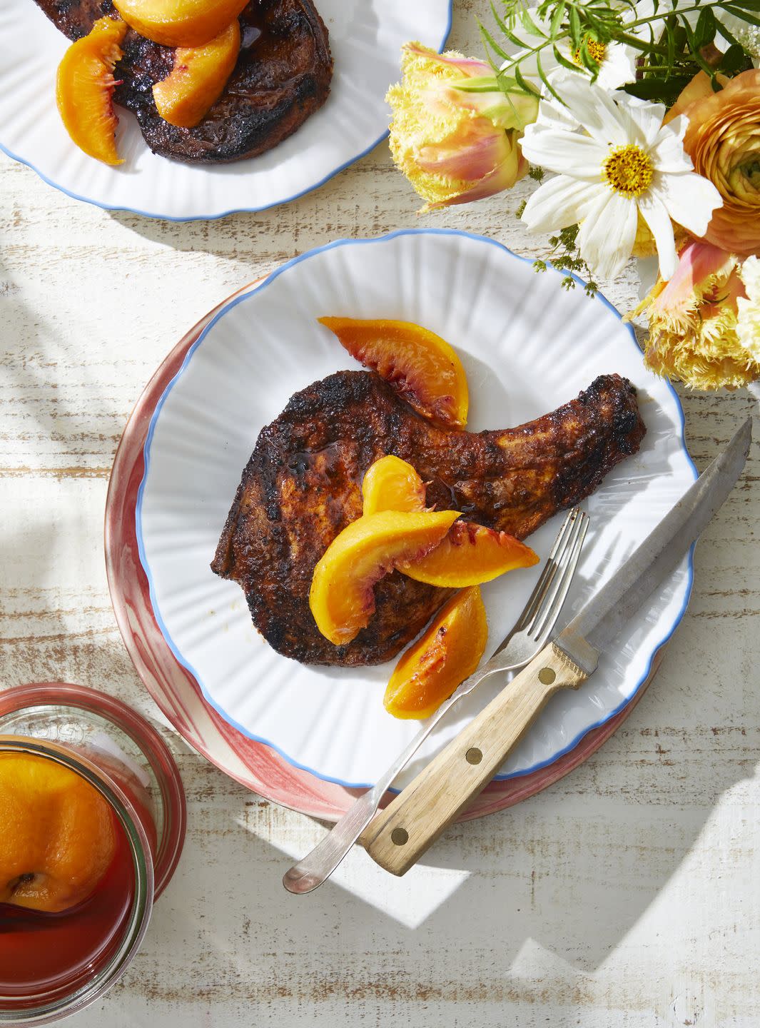 a plate of grilled pork chops with whole pickled peaches