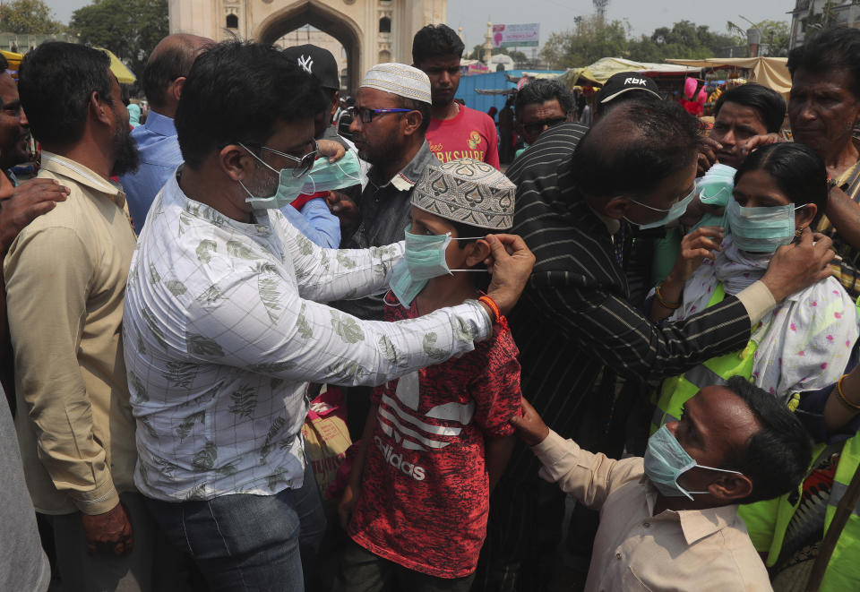 Indian social activists distribute masks to pedestrians at the landmark Charminar in Hyderabad, India, Thursday, March 5, 2020. (AP Photo/Mahesh Kumar A.)