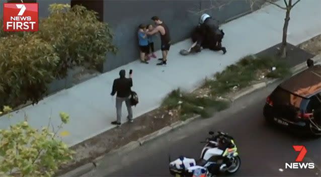 A passersby attempts to console the children as their father is arrested. Source: 7 News