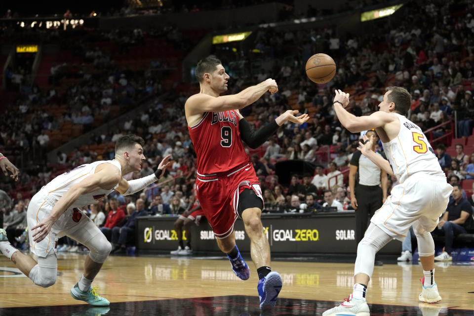 Chicago Bulls center Nikola Vucevic (9) passes the ball as Miami Heat guard Tyler Herro, left, and forward Duncan Robinson, right, defend during the first half of an NBA basketball game, Tuesday, Dec. 20, 2022, in Miami. (AP Photo/Lynne Sladky)