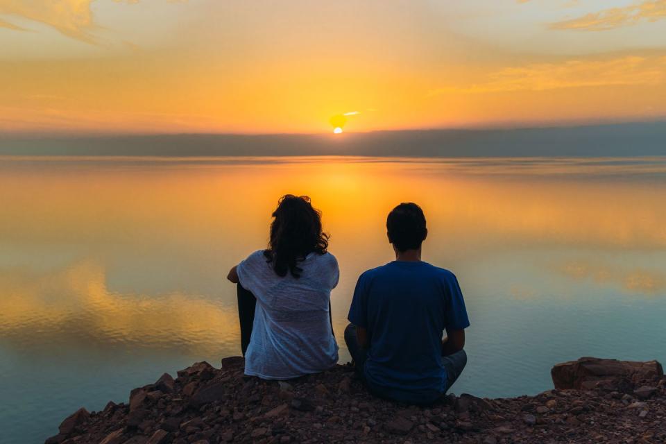 happy young female and male contemplating the scenic sunset above the dead sea in jordan