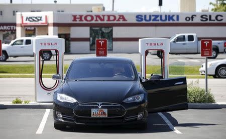 A man charges his Tesla Model S at a charging stations in a lot at a new Tesla dealership across from a traditional car dealer in Salt Lake City May 29, 2015. REUTERS/George Frey