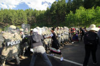 Protesters clash with a line of law enforcement officers in Keystone, S.D., on the road leading to Mount Rushmore ahead of President Donald Trump's visit to the memorial on Friday, July 3, 2020. (AP Photo/Stephen Groves)