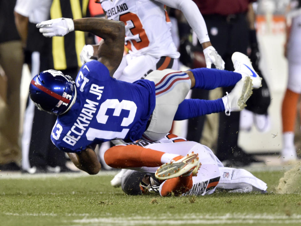 FILE - In this Aug. 21, 2017, file photo, New York Giants wide receiver Odell Beckham (13) is tackled by Cleveland Browns strong safety Briean Boddy-Calhoun in the first half of an NFL preseason football game in Cleveland. Odell Beckham Jr. says former Browns defensive coordinator Gregg Williams instructed his players to "take me out" of a preseason game in 2017. The Pro Bowl wide receiver sustained an ankle injury when Cleveland's Briean Boddy-Calhoun cut his legs out while he was with the New York Giants. Beckham said current Cleveland players told him that Williams instructed them to "take me out of the game, and it's preseason." (AP Photo/David Richard, File)