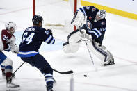 Winnipeg Jets goaltender Connor Hellebuyck (37) clears the puck as Logan Stanley (64) defends against Colorado Avalanche's Ross Colton (20) during the first period in Game 2 of an NHL hockey Stanley Cup first-round playoff series Tuesday, April 23, 2024, in Winnipeg, Manitoba. (Fred Greenslade/The Canadian Press via AP)