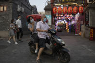 Residents wearing masks to curb the spread of the coronavirus past by lanterns and neon lights promoting a restaurant in Beijing on Friday, June 26, 2020. Even as Beijing appears to have contained the latest outbreak, businesses are still reeling from the prolonged impact of the coronavirus on the economy. (AP Photo/Ng Han Guan)