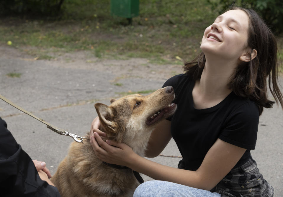 A girl plays with a dog in a pet shelter in Kyiv, Ukraine, Tuesday, July 19, 2022. Shellshocked family pets started roaming around Ukraine's capital with nowhere to go in the opening stages of Russia's war. Volunteers opened a shelter to take them in and try to find them new homes or at least some human companionship. (AP Photo/Efrem Lukatsky)