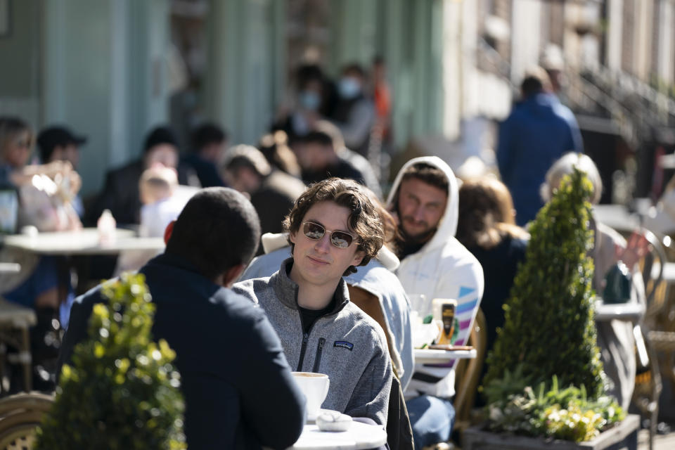 Customers sit outside a restaurant in Liverpool, Monday, April 12, 2021, as restaurants, bars and pubs can open and serve people who can be seated outside. Millions of people in England will get their first chance in months for haircuts, casual shopping and restaurant meals on Monday, as the government takes the next step on its coronavirus lockdown-lifting road map. (AP Photo Jon Super)