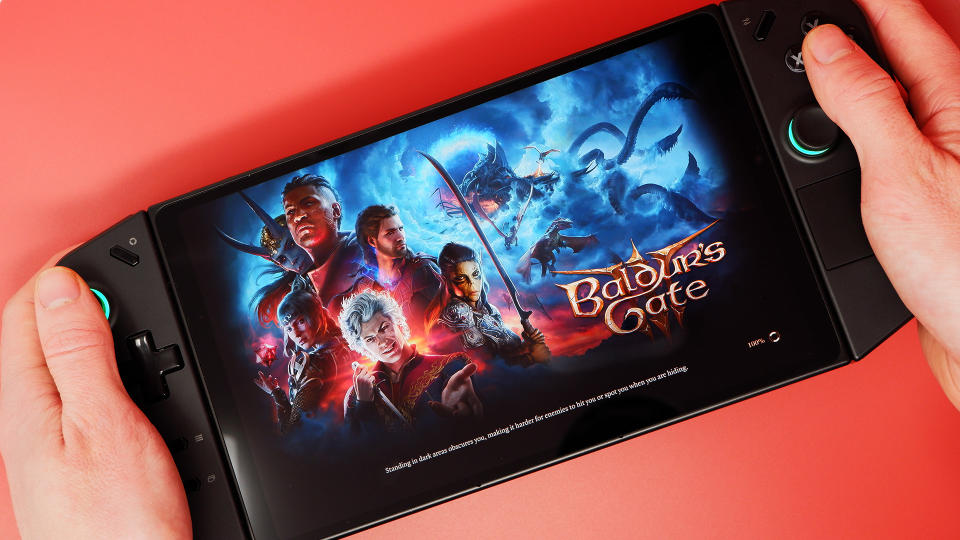 The Lenovo Legion Go on a red background and playing Baldur's Gate 3.