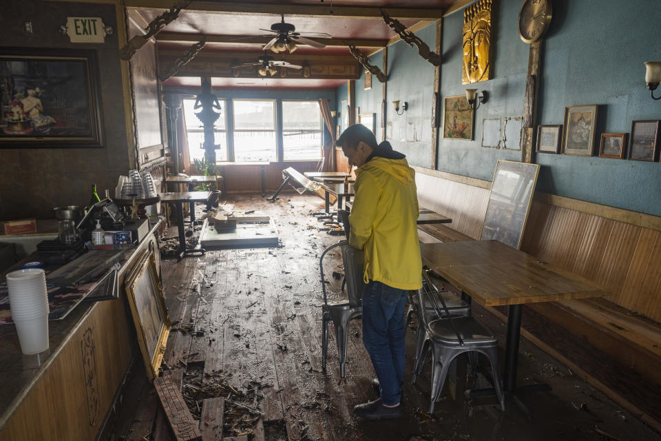 Dominic King, owner of My Thai Beach, surveys storm damage that destroyed his restaurant in Capitola, Calif., Thursday, Jan. 5, 2023. Damaging hurricane-force winds, surging surf and heavy rains from a powerful “atmospheric river” pounded California on Thursday, knocking out power to tens of thousands, causing flooding, and contributing to the deaths of at least two people, including a child whose home was hit by a falling tree. (AP Photo/Nic Coury)