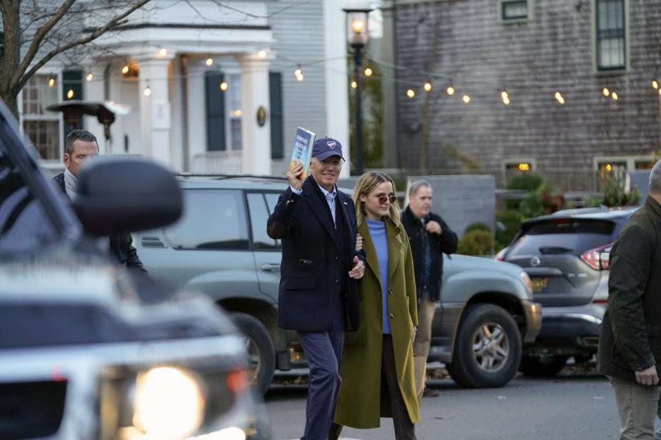 President Joe Biden holds a copy of "Democracy Awakening" by Heather Cox Richardson as he walks with his granddaughter Finnegan Biden while they visit shops in Nantucket, Mass., Friday, Nov. 24, 2023. (AP Photo/Stephanie Scarbrough)