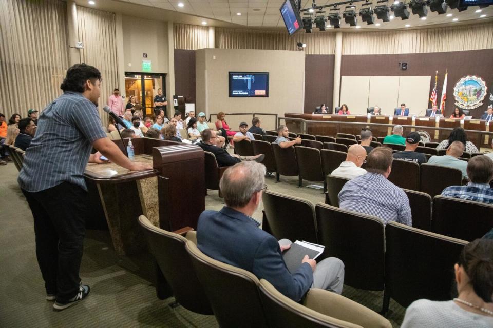 A man speaks into a microphone before a city council.