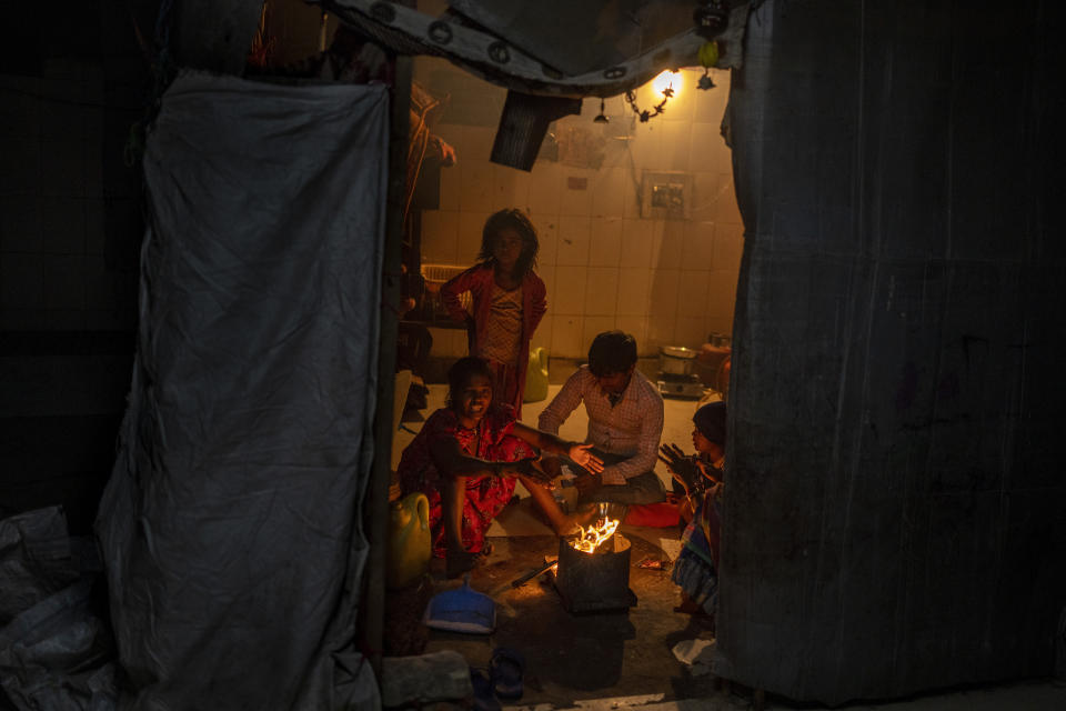 A homeless family sit around a bonfire inside a dilapidated shelter for homeless people on a cold night in New Delhi, India, Dec. 28, 2022. Even though the city’s night shelters are a refuge to many who would otherwise find themselves sleeping near traffic-busy roundabouts and underpasses, most people there live in harsh conditions. (AP Photo/Altaf Qadri)