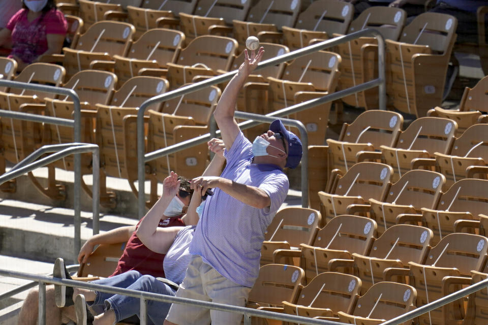 A fan reaches up to catch a foul ball hit by San Francisco Giants' Curt Casali during the fourth inning of the team's spring training baseball game against the Chicago White Sox on Monday, March 22, 2021, in Phoenix. (AP Photo/Ross D. Franklin)