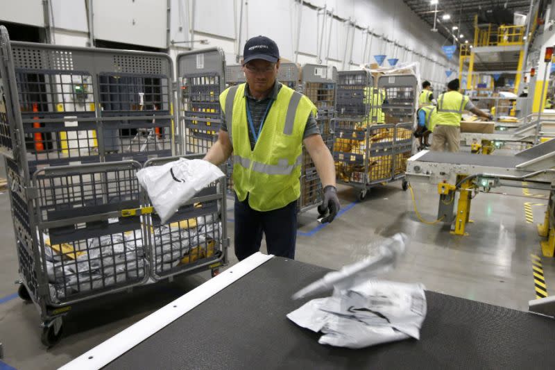 En esta foto del 17 de diciembre de 2019, Steven Smith coloca los paquetes en una cinta transportadora antes de que los robots de Amazon lleven esos paquetes a conductos organizados por código postal, en un almacén de Amazon en Goodyear, Arizona (Foto AP/Ross D. Franklin)