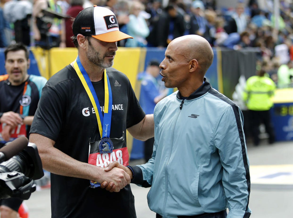 NASCAR star Jimmie Johnson, left, completed the Boston Marathon on Monday and received his medal from race marshal and 2014 champion Meb Keflezighi. (AP)
