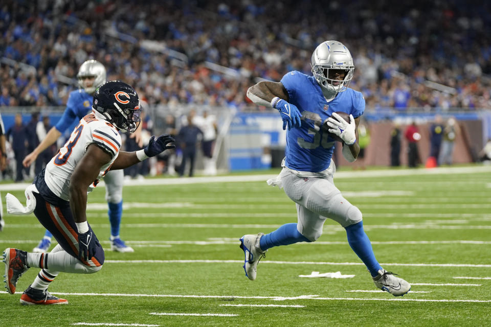 Detroit Lions running back Jamaal Williams (30), defended by Chicago Bears linebacker Nicholas Morrow (53), runs for a 2-yard touchdown during the second half of an NFL football game, Sunday, Jan. 1, 2023, in Detroit. (AP Photo/Paul Sancya)