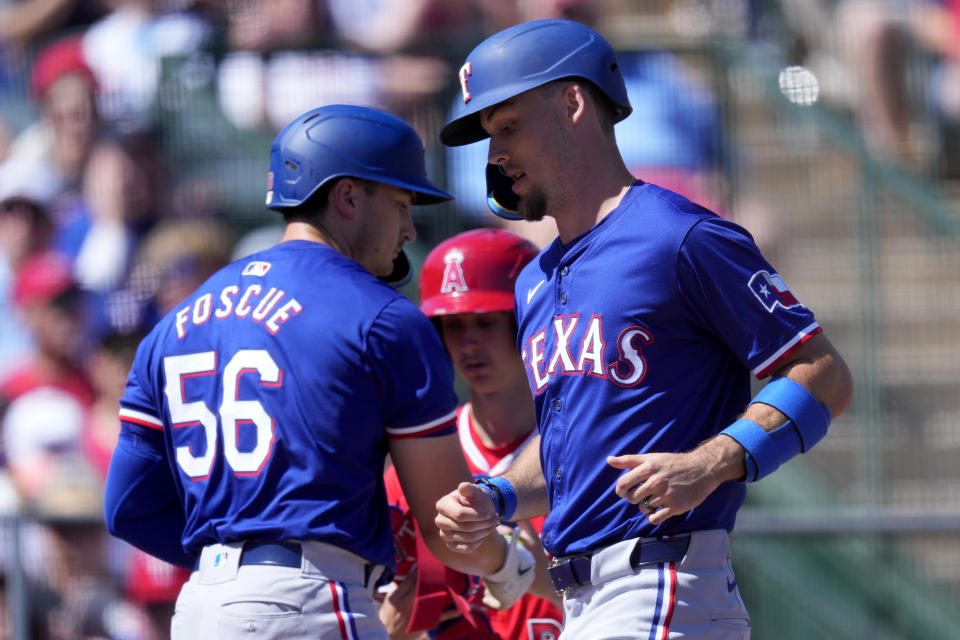 Texas Rangers' Evan Carter scores on a bases loaded walk during the first inning of a spring training baseball game against the Los Angeles Angels, Monday, March 11, 2024, in Tempe, Ariz. (AP Photo/Matt York)