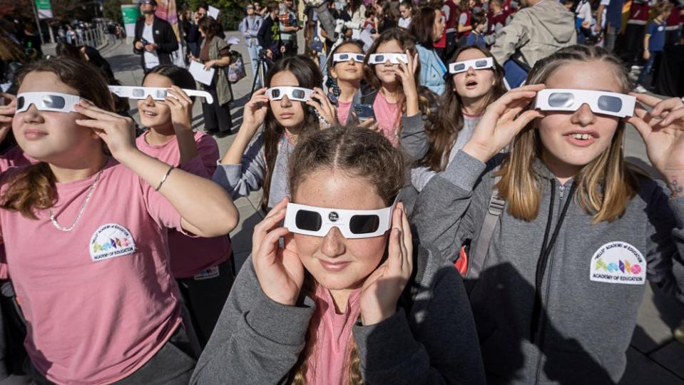 Students wearing special glasses observe a partial solar eclipse in Kosovo capital Pristina on Tuesday, Oct. 25, 2022.